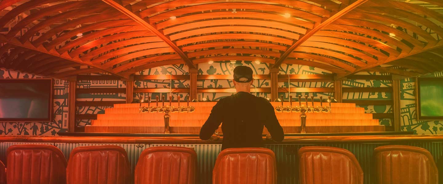 banner image of a customer sitting at a bar with his back to the camera